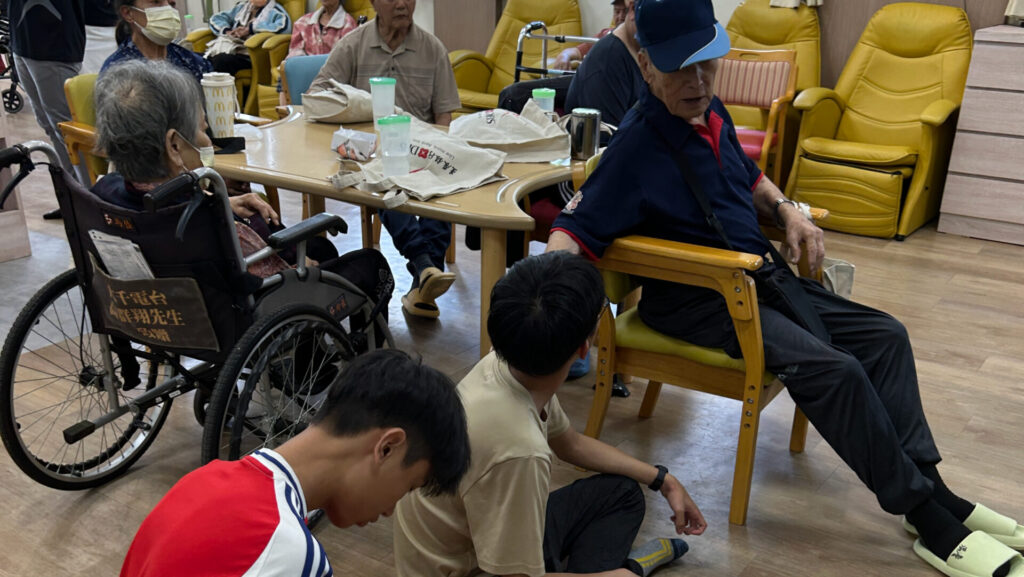 在雙崎日照中心,學生陪伴長輩聊天、活動,在一來一往的互動中聽見不同的人生故事,也看見照服員如何透過陪伴與復能支持,讓長輩在熟悉的土地上健康生活、保有尊嚴。圖片來源:臺北市無界塾實驗教育機構。