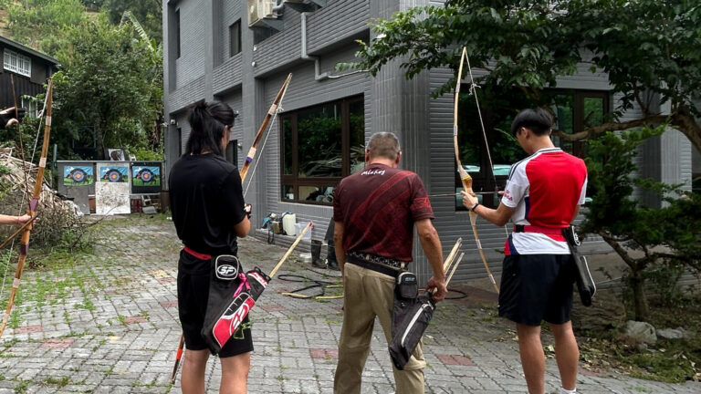 熱情的部落長者引導孩子使用傳統弓箭,其實這場體驗並不是事先安排好的行程,而是在馬路邊閒聊後,偶然促成的機緣,這也是移地學習有趣的地方。圖片來源:臺北市無界塾實驗教育機構。